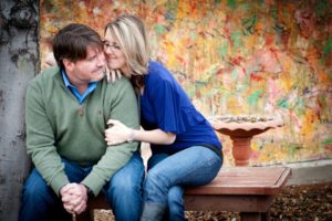 Couple sitting on bench, colorful background.