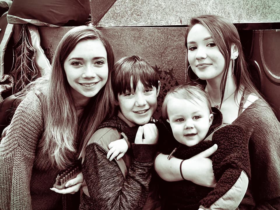 Four people posing, smiling, close together.