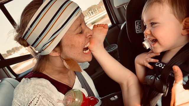 Woman and baby smiling in car seat.